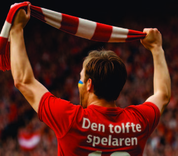 Bilden på Specialkortet Supportern: en supporter bakifrån i röd tröja med texten Den tolfte spelaren håller upp en randig halsduk på en fullsatt läktare